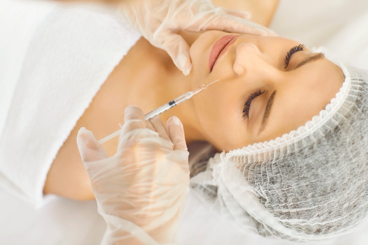 Young,Woman,In,Medical,Cap,Receives,Aesthetic,Face,Treatment,Done