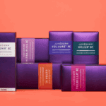 Juvederm collection of dermal hyaluronic acid fillers display of boxes, clockwise from left: Juvederm Voluma XC, Juvederm Ultra Plus XC, Juvederm Vollure XC, Juvederm Volux XC, Juvederm Volbella XC, and Juvederm Ultra XC on orange background